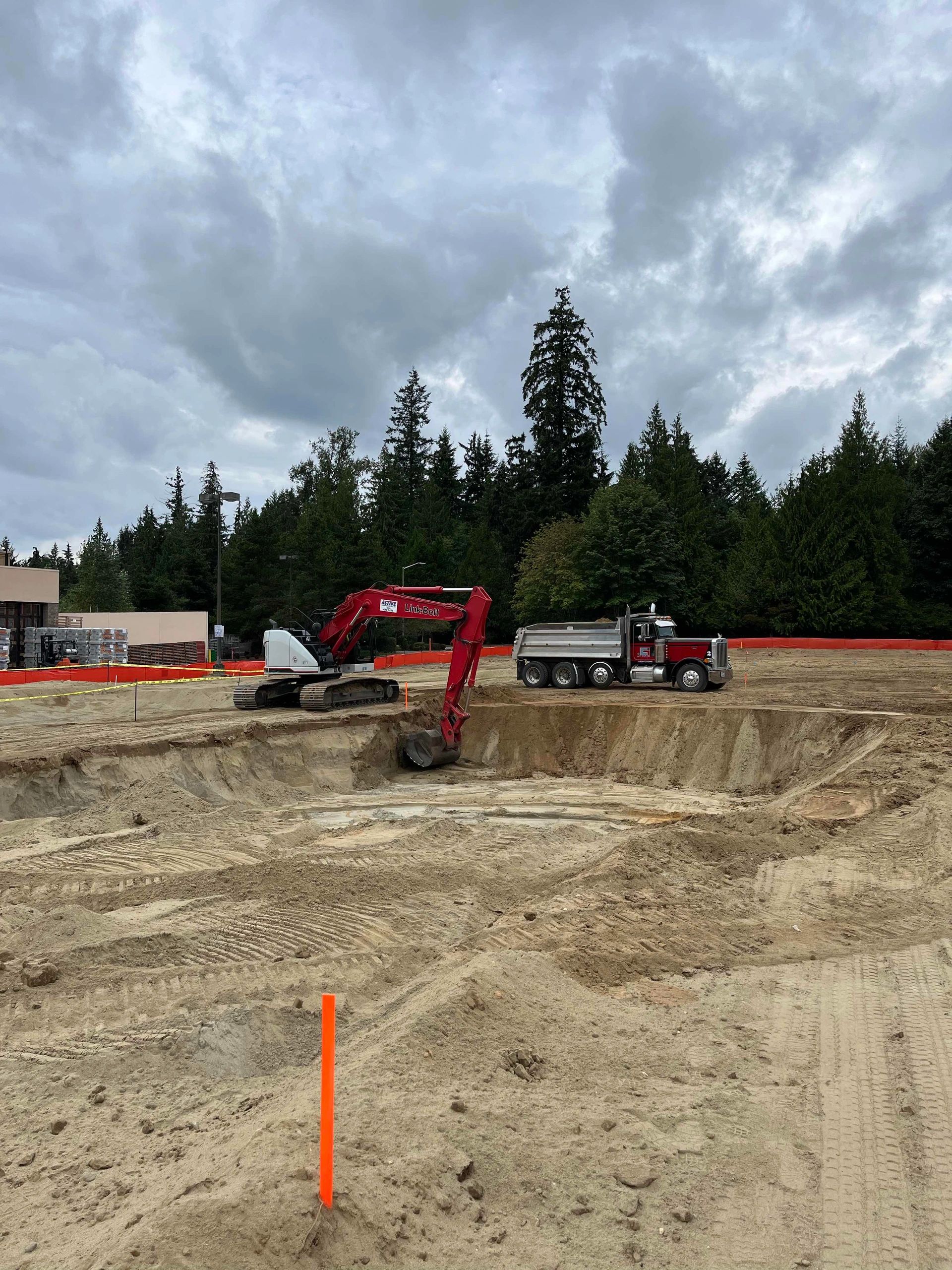 Red excavator and dump truck at active construction site